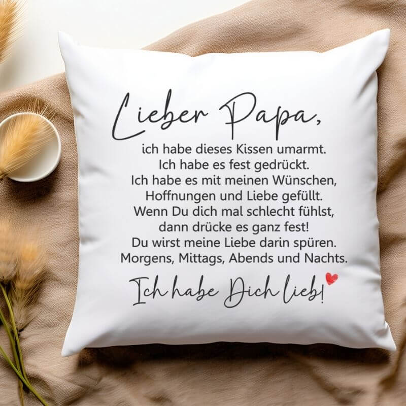 Flauschiges Kissen „Lieber Papa – Kissen umarmt“ in Ich-Form mit Spruch, liebevoll inszeniert mit Hafergräsern und Tasse.