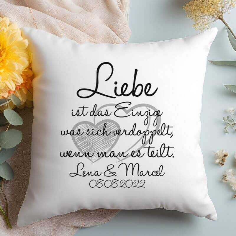 Personalisiertes Kissen mit Spruch über die Liebe und zwei Herzen, mit Blumen und einer Decke dekoriert