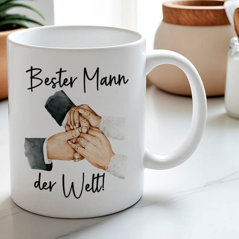 Keramiktasse „Bester Mann der Welt“ mit Aquarellmotiv von Händen eines Paares auf einem hellen Tisch mit Deko im Hintergrund