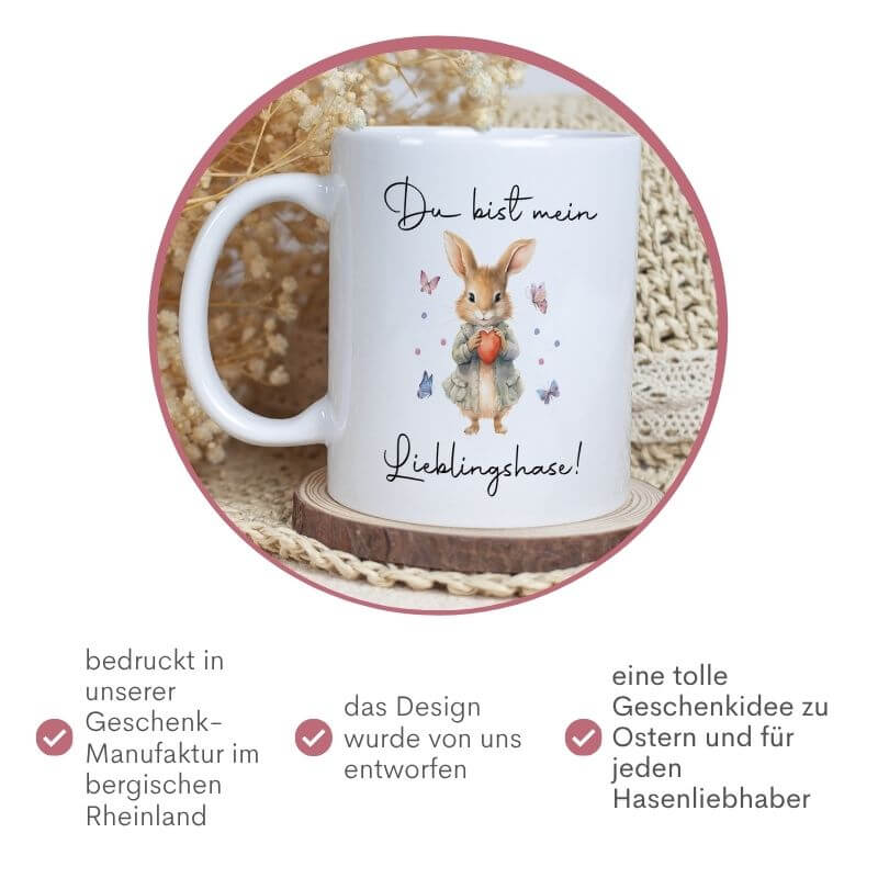 Weiße Tasse mit Aquarellmotiv eines Hasen, der ein rotes Herz hält, umgeben von Schmetterlingen und dem Schriftzug "Du bist mein Lieblingshase!"– liebevolle Geschenkidee zu Ostern oder für Hasenliebhaber.